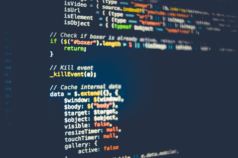 A close-up view of a person's hand with a wristwatch, typing on a silver laptop with a black keyboard. The screen displays lines of code with various syntax elements in different colors. The laptop is